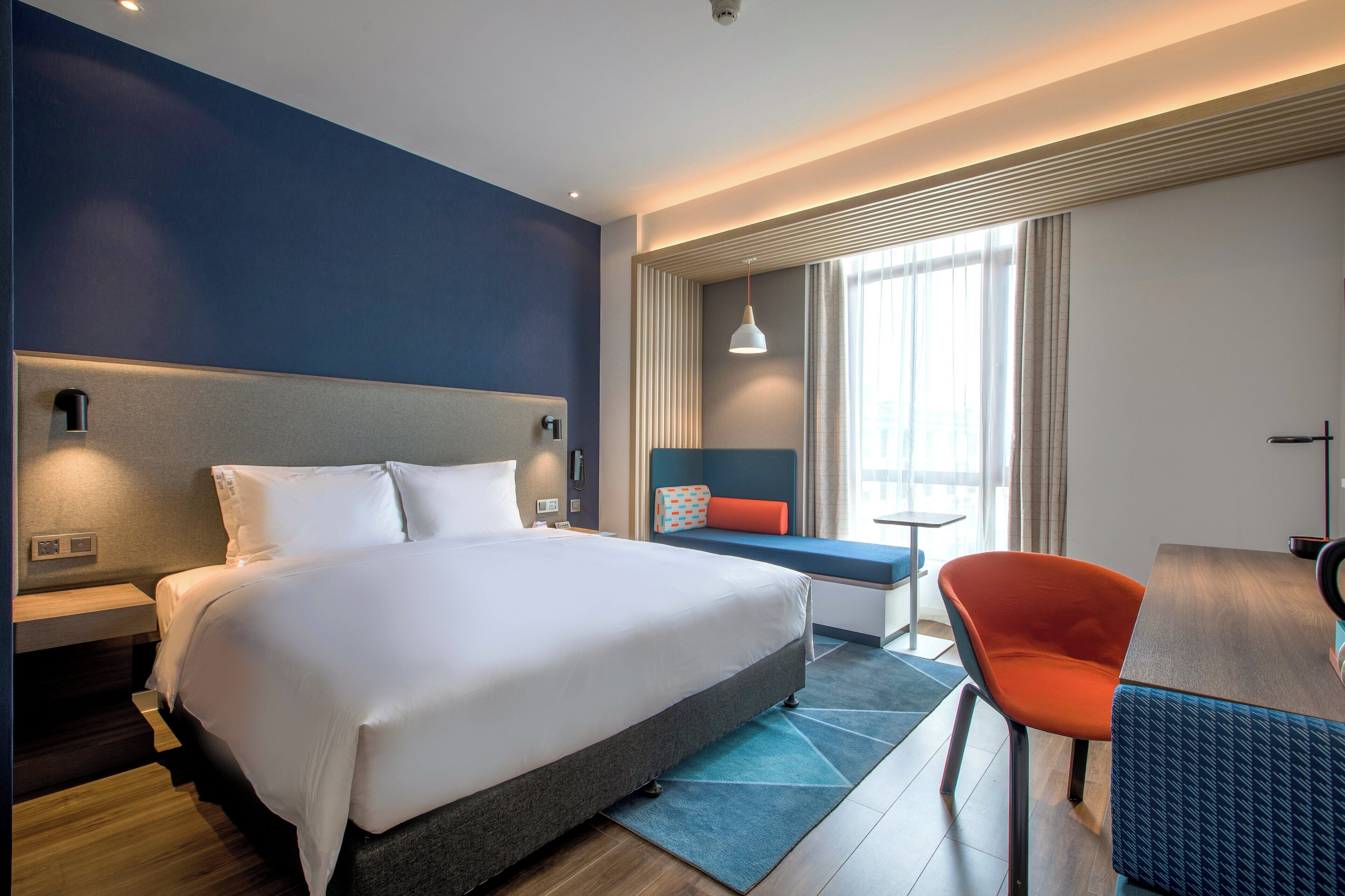 Una habitación de hotel moderna con una cama grande, una zona de estar con vistas y un escritorio.