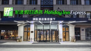 L’extérieur d’un hôtel Holiday Inn Express, avec un logo vert bien visible et une signalétique indiquant qu’il fait partie du groupe hôtelier Holiday Inn Express.