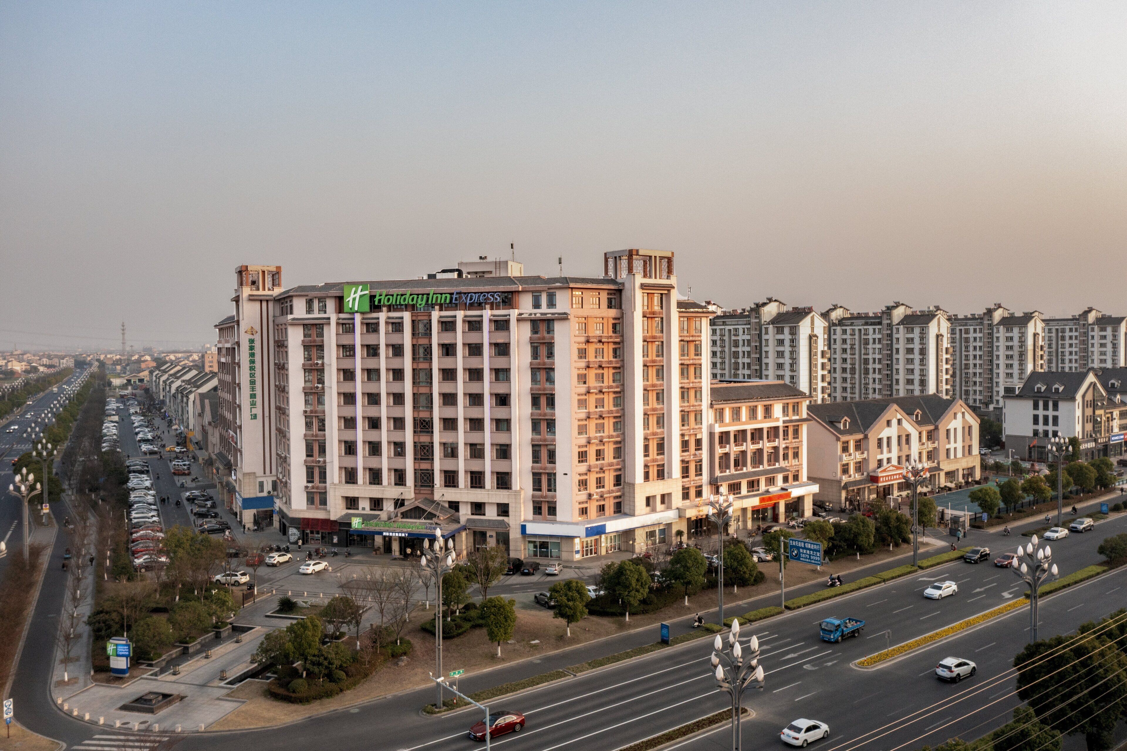 A multi-story hotel with a prominent sign, surrounded by a busy urban street with cars and pedestrians.