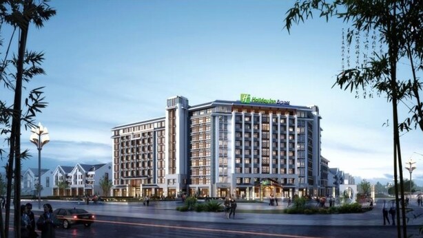 Un hôtel à plusieurs étages au design moderne, doté d’une entrée imposante et d’une enseigne indiquant qu’il s’agit d’un Holiday Inn Express.