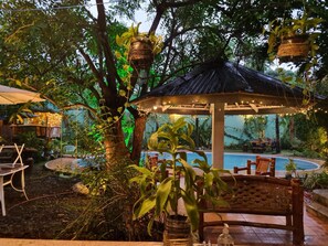 A gazebo with string lights, a pool, and outdoor seating.