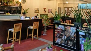 Eine Hotelhalle mit Holzsesseln, einer Rezeption und verschiedenen Topfpflanzen.