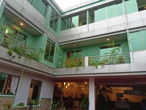 Un immeuble à plusieurs étages doté de balcons, de grandes fenêtres et d’un espace d’entrée abrité.