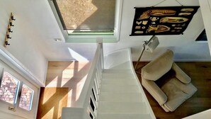 Un intérieur moderne avec un escalier menant à une mezzanine, un canapé et une œuvre d’art accrochée au mur.
