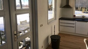 Une cuisine avec une fenêtre, une cuisinière et une poubelle.