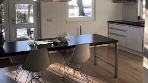 Une cuisine moderne avec un coin repas, dotée d’une grande fenêtre, d’un luminaire suspendu et d’un escalier.