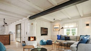 A living room with a fireplace, sofa, coffee table, and a view of the outdoors.