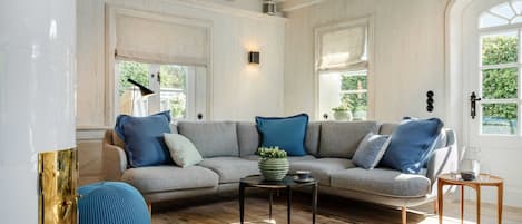 A living room with a sectional sofa, a coffee table, and a round wooden table.