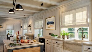 A kitchen with wooden cabinets, a central island, and a window with a view of greenery.
