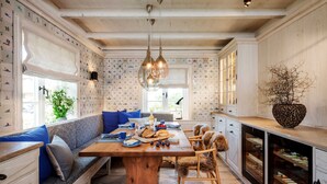 A kitchen with a wooden table, blue upholstered bench, and a built-in wine rack.