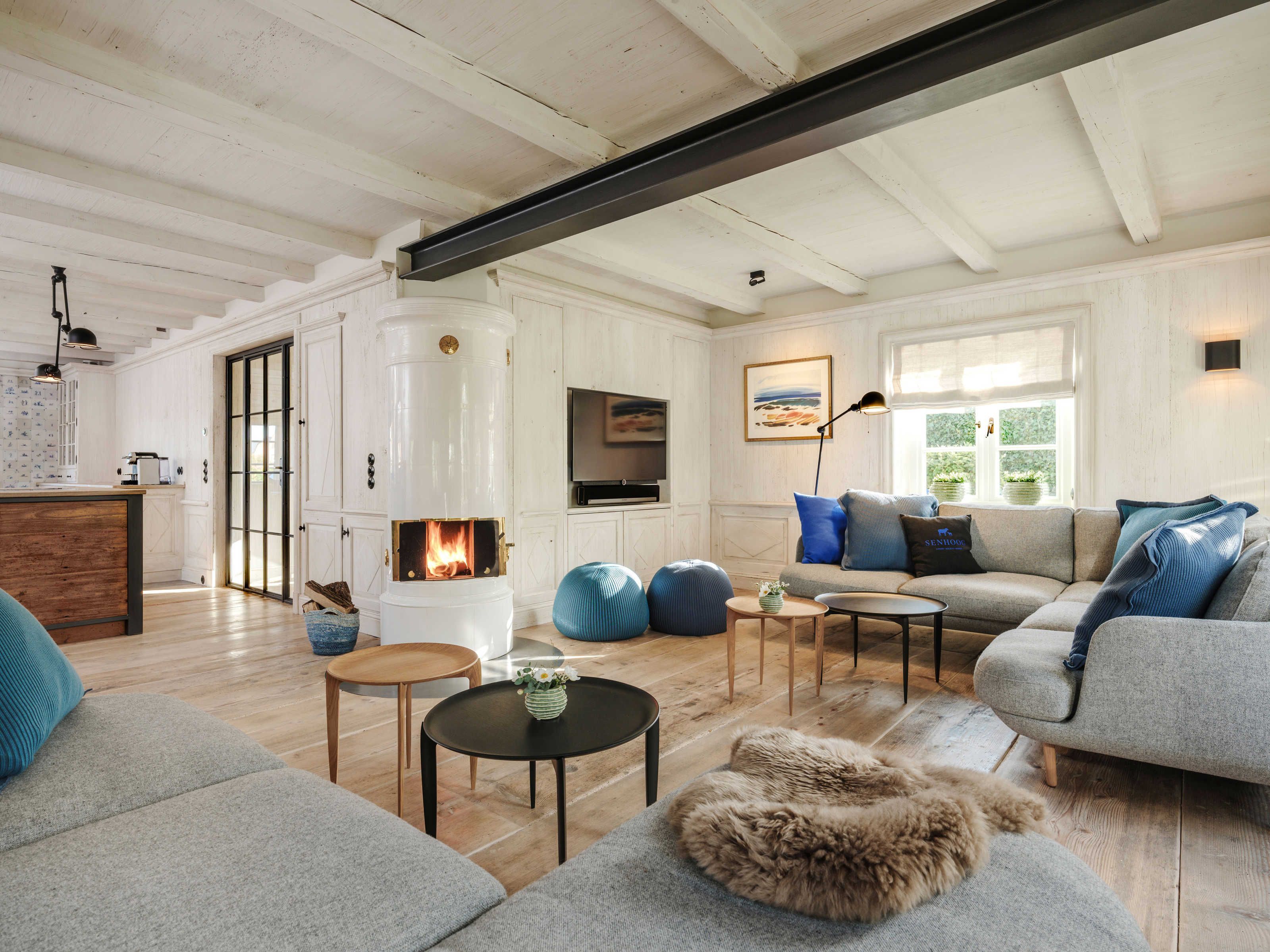 Un salon avec une cheminée, un canapé, une table basse et une vue sur l’extérieur.