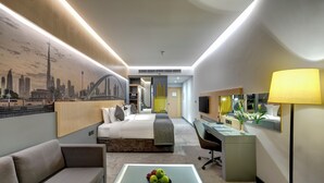 Een moderne hotelkamer met een bed, een bank, een bureau en een salontafel met fruit.