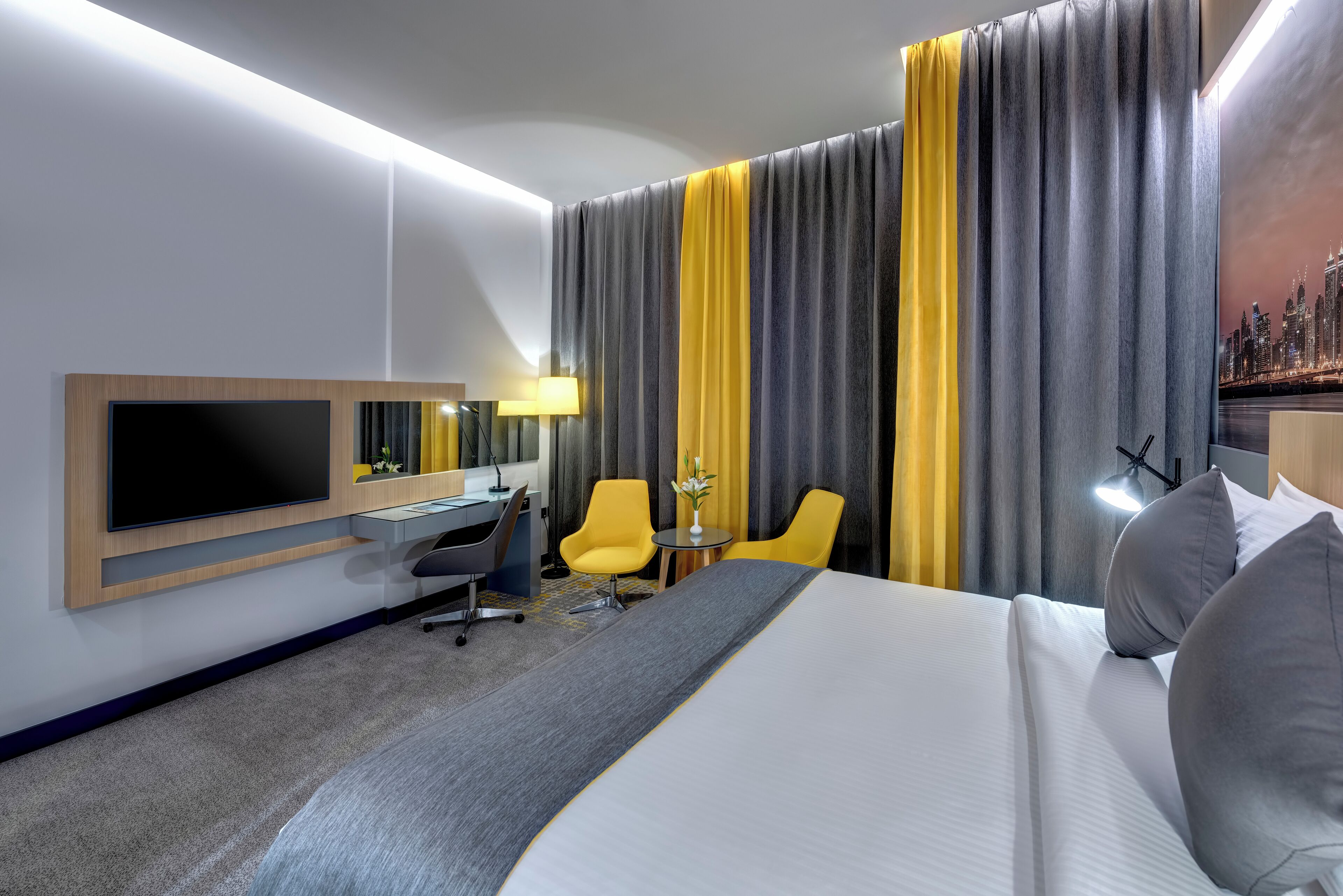 A hotel room with a bed, a desk, a chair, a TV, and curtains.