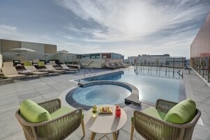 Una piscina al aire libre, sombrillas, sillones reclinables de piscina