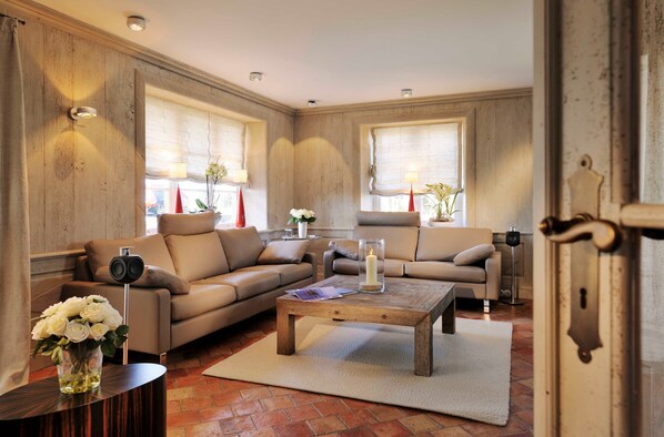 A spacious living room with a large sectional sofa, a wooden coffee table, and a small side table with a vase of flowers.