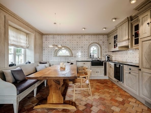 A spacious kitchen with a wooden dining table, a built-in bench, and a large window.