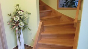 Un escalier en bois, avec un rideau blanc et un arrangement floral à côté.