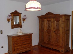 Et værelse med et trækommode, en stor garderobe, et spejl og en hængende lampe.