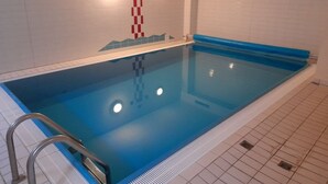 Een zwembad met een trap, betegelde wanden en een eenvoudige decoratie.