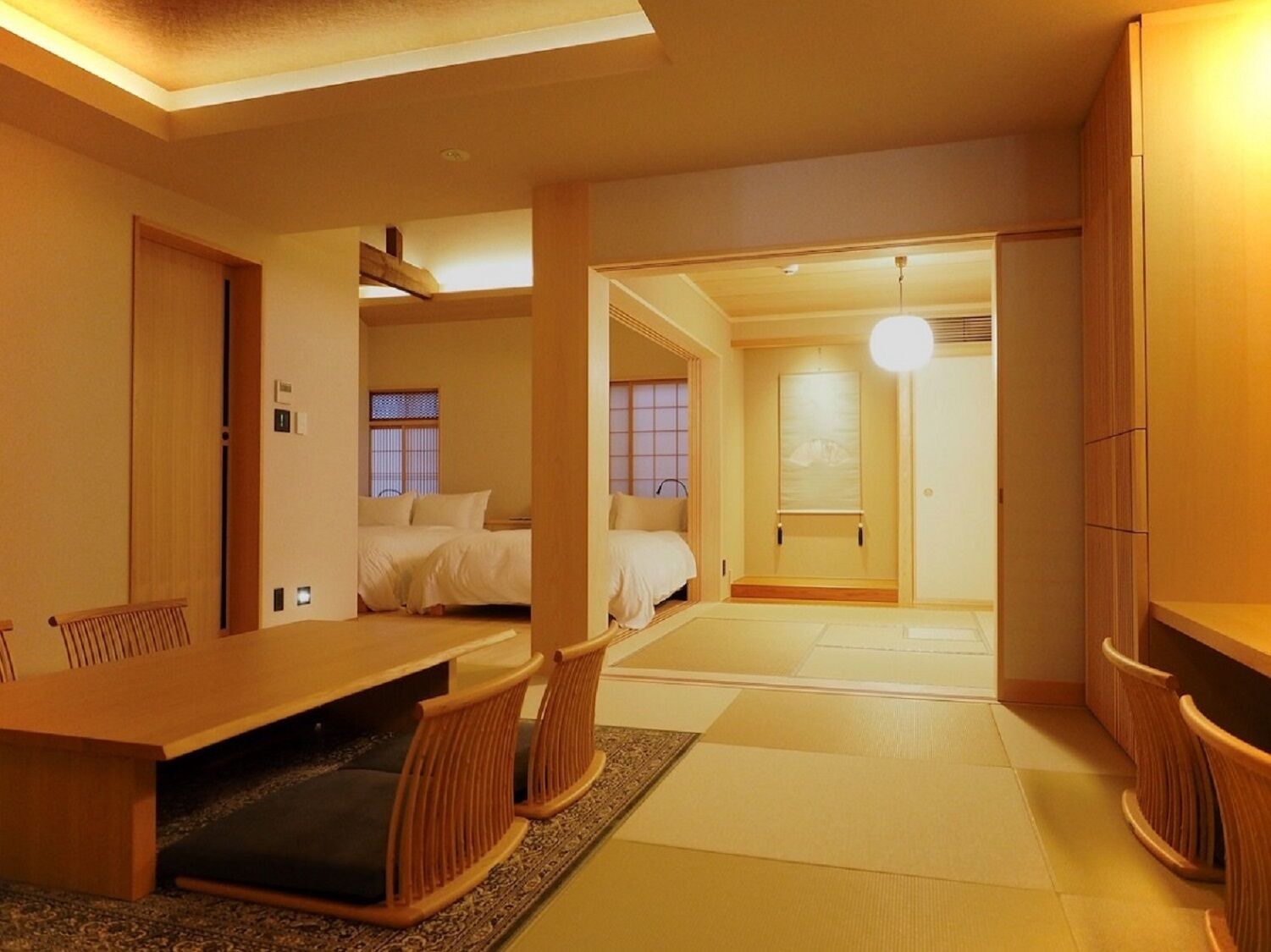 A traditional Japanese-style room with tatami flooring, a low table with cushions, and a sliding door leading to another room.