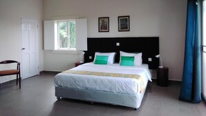 A bedroom with a bed, a chair, a window, and a door. - Koh Ker Hotel & Restaurant (Kuleaen)