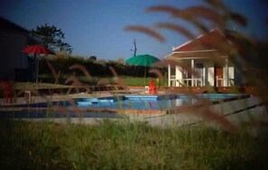 A swimming pool with a covered area, a building with a porch, and a clear sky. - Koh Ker Hotel & Restaurant (Kuleaen)