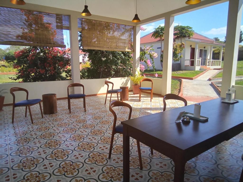 Uma área de pátio coberta com mesa e cadeiras, piso estampado e vista para uma casa e jardim.