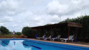 A swimming pool with clear blue water, surrounded by lounge chairs and a covered seating area. - Koh Ker Hotel & Restaurant (Kuleaen)