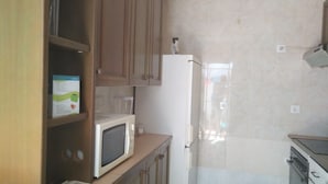 A kitchen with wooden cabinets, a white refrigerator, and a microwave. - Cozy and central bass (Ciudad Real)