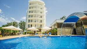 A swimming pool with a water fountain, lounge chairs, and umbrellas. - Kobuleti Pearl Of Sea Hotel & Spa (Kobuleti)