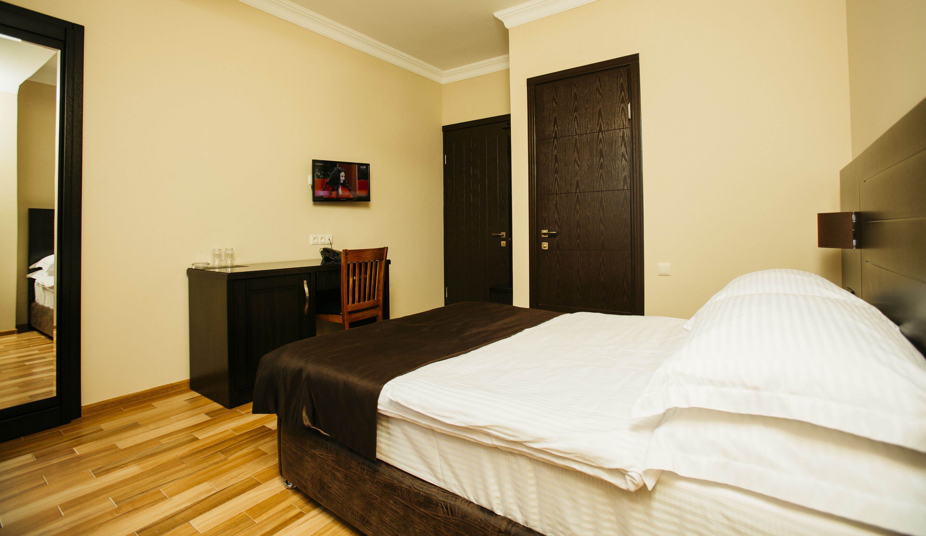 A bedroom with a bed, a desk, a chair, and two doors.