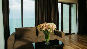 A brown sofa with a glass vase of flowers on a black table, positioned in front of a large window with a view of the sea. - Kobuleti Pearl Of Sea Hotel & Spa (Kobuleti)