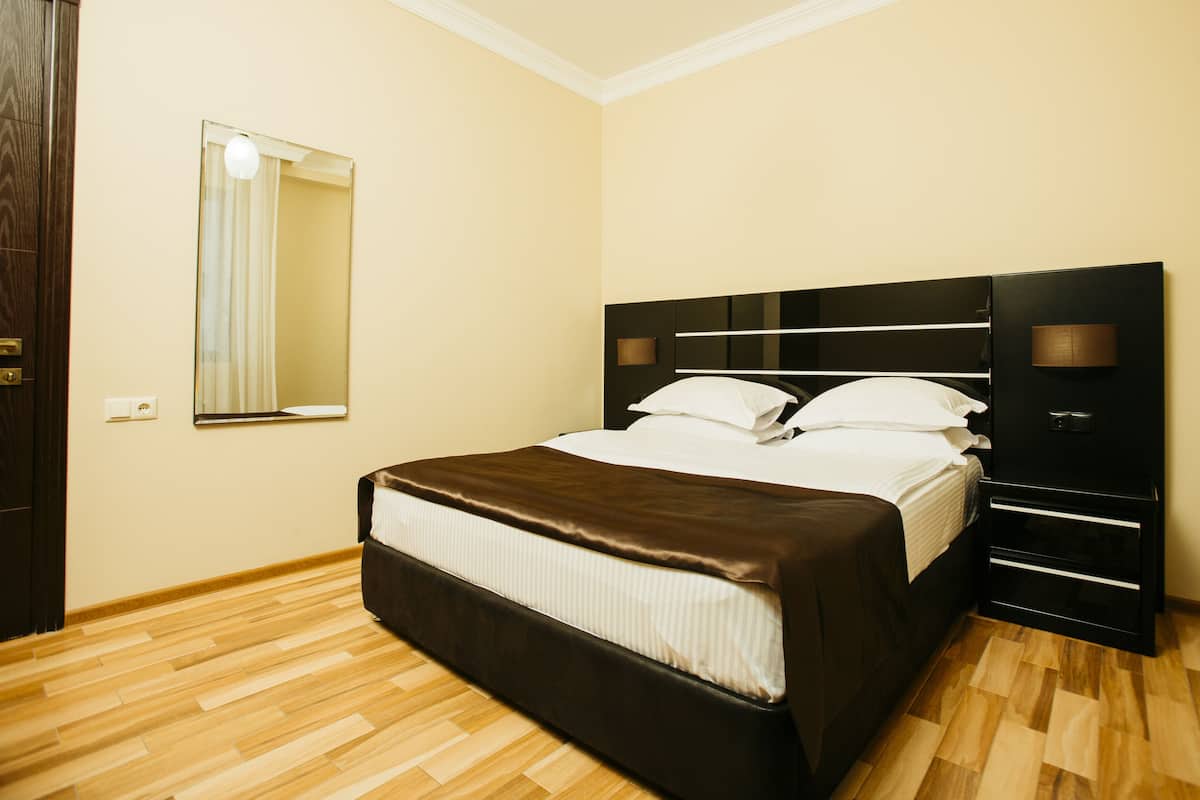 A bedroom with a bed, a nightstand, a mirror, and a wardrobe.
