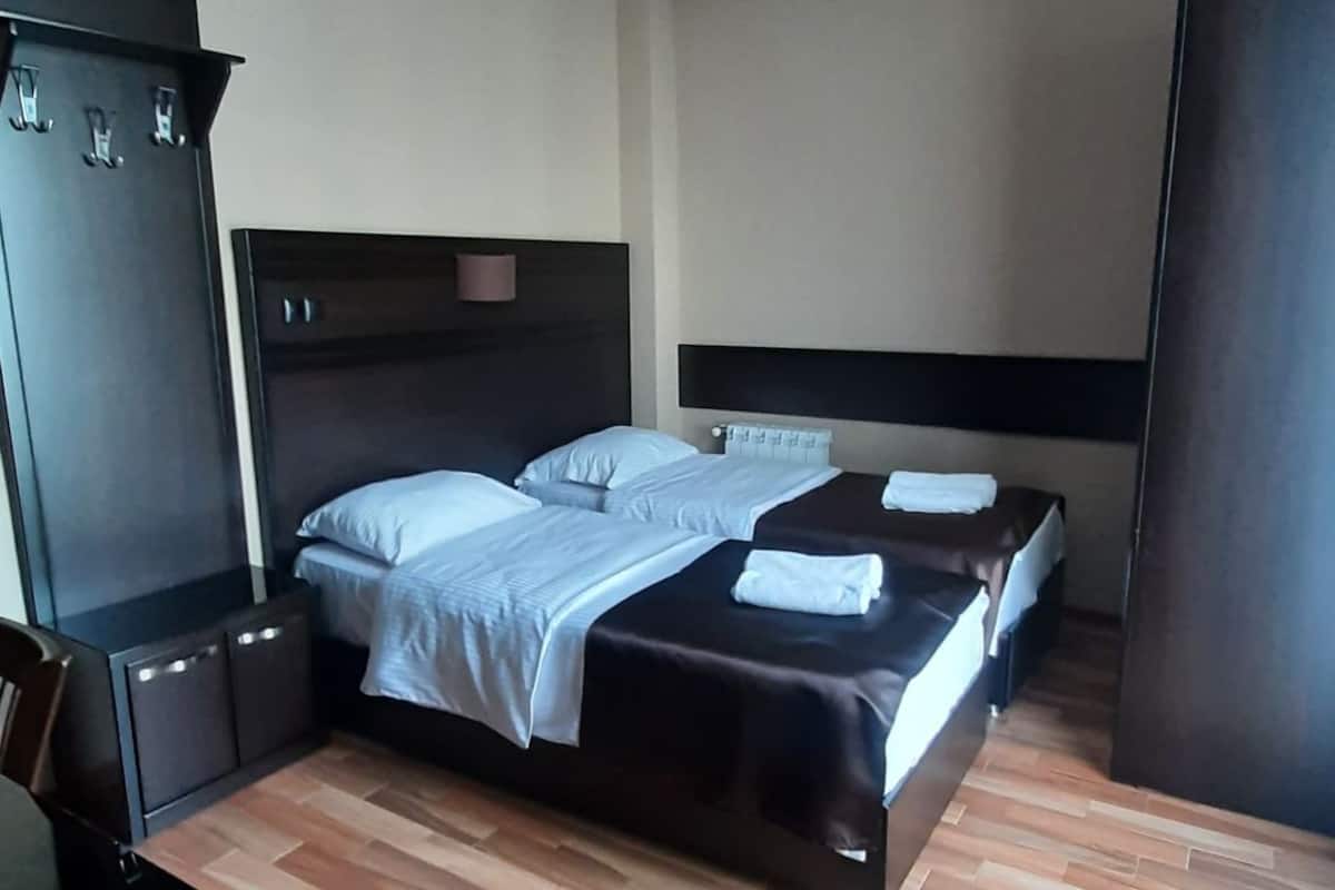 A hotel room with a bed, a wardrobe, and a desk.
