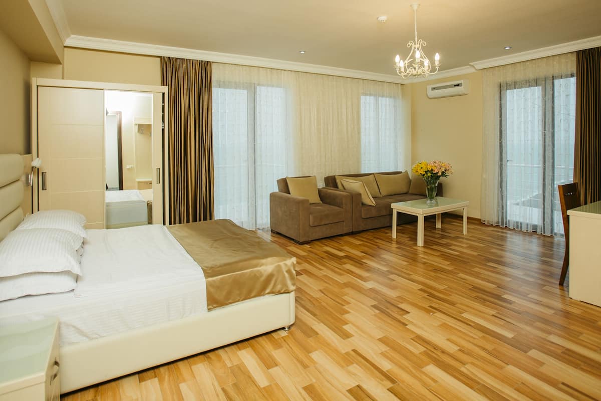 A hotel room with a bed, a sofa, a coffee table, and a desk.