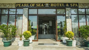 The exterior of the Pearl of Sea Hotel & Spa, featuring a prominent entrance with glass doors, potted plants, and a clear view of the interior through the windows. - Kobuleti Pearl Of Sea Hotel & Spa (Kobuleti)