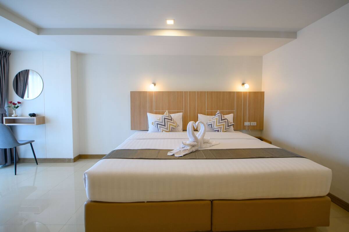 A hotel room with a large bed, two bedside tables, a desk, and a chair.