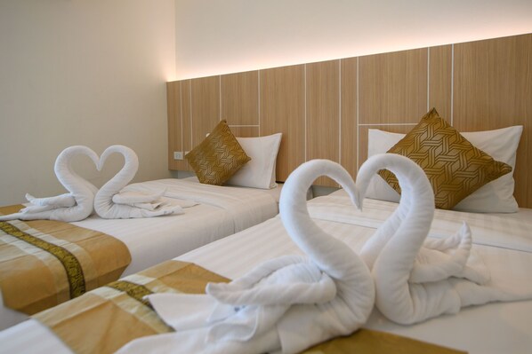 A hotel room with two beds, each adorned with white towels shaped like swans. - Iris palace (Pattaya)