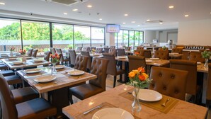 Um restaurante com várias mesas, cada uma posta com pratos, talheres e vasos de flores.