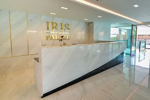 A reception desk with a marble surface and a glass partition. - Iris palace (Pattaya)