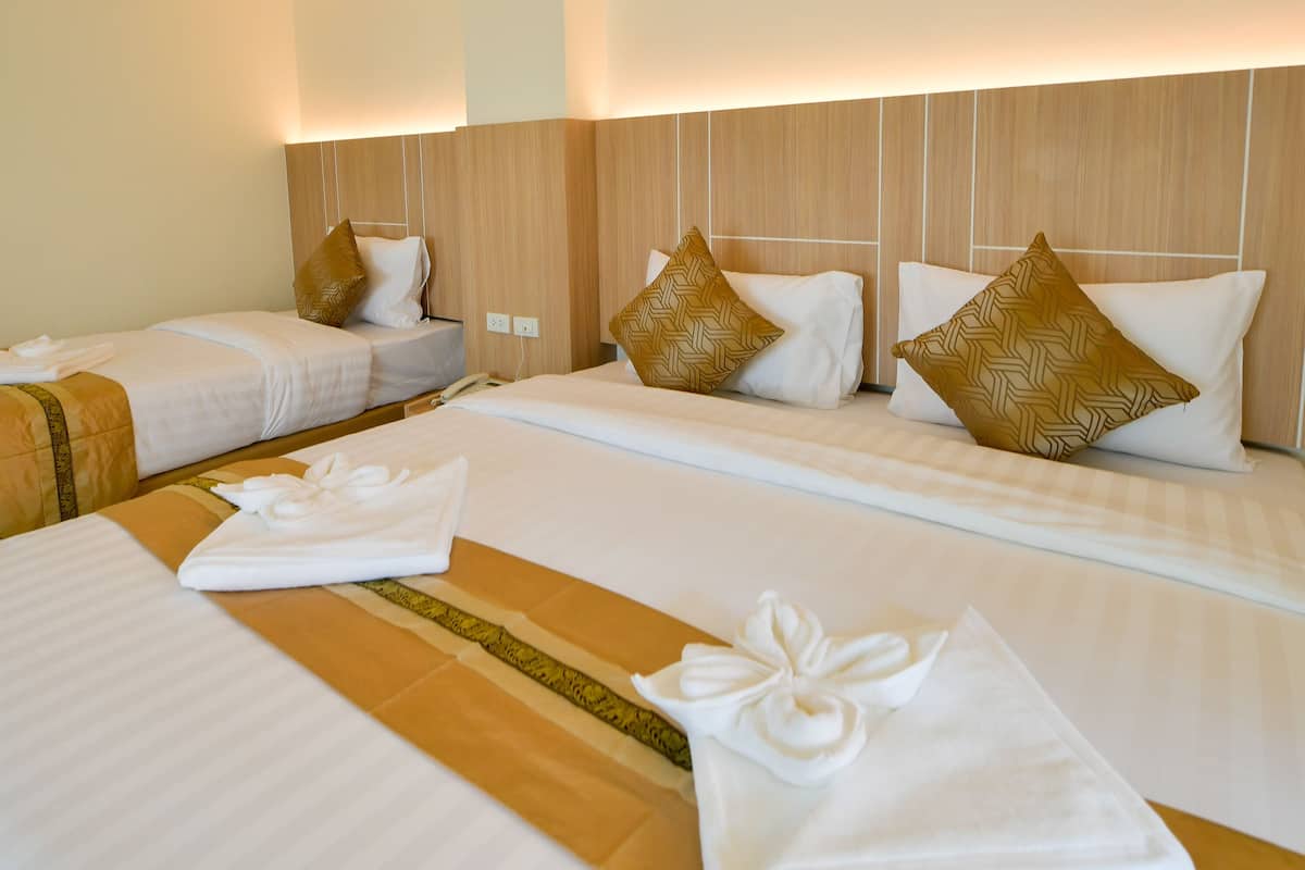 A hotel room with two beds, each with white linens and decorative pillows. There is a wooden headboard and a visible power outlet on the wall.