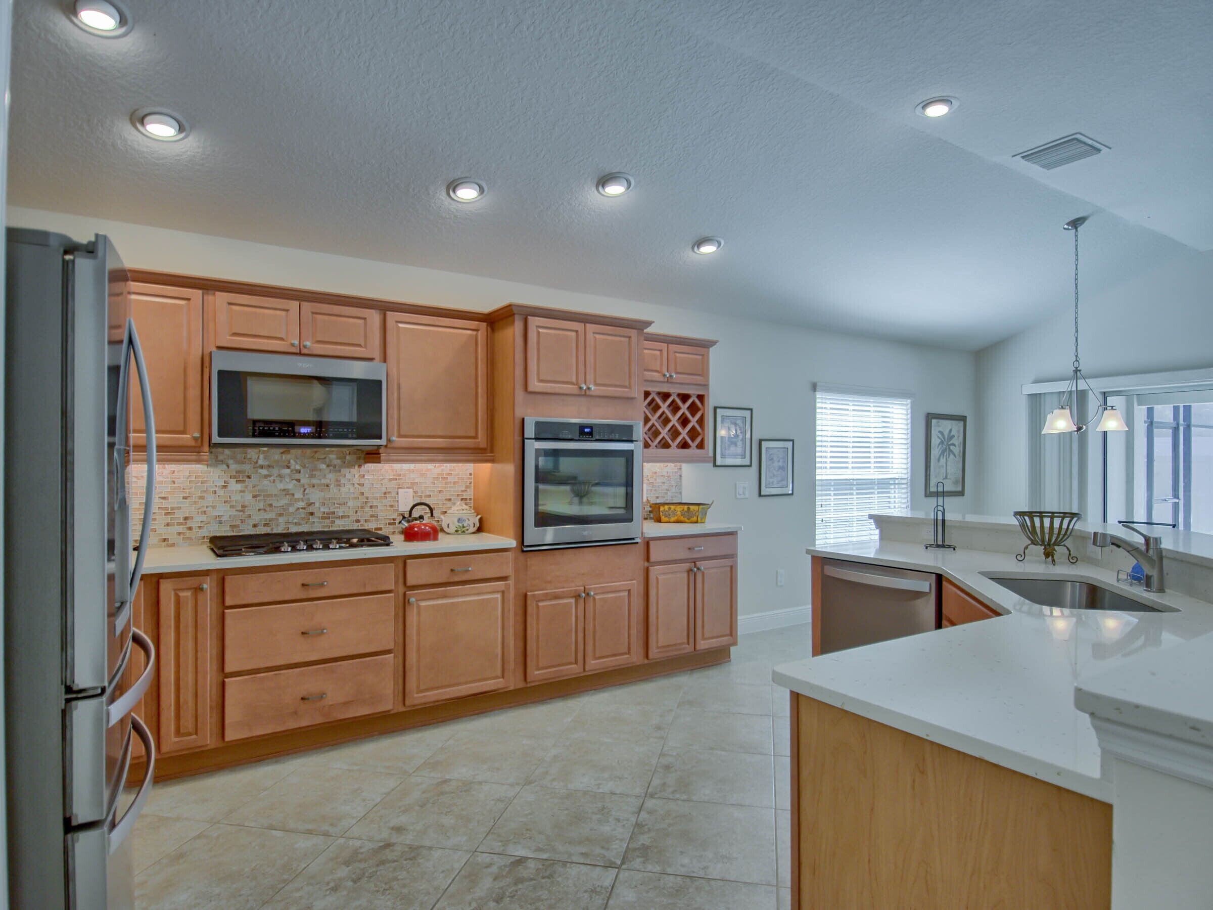 A modern kitchen with wooden cabinets, stainless steel appliances, and a large island.