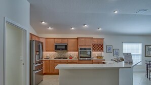 Cocina moderna con armarios de madera, electrodomésticos de acero inoxidable y una isla central.