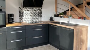 A modern kitchen with black cabinets, a wooden countertop, a built-in stove, and a black backsplash.