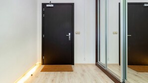 Ein modernes Zimmer mit einer dunklen Tür, einer Glastrennwand und einem Holzboden.