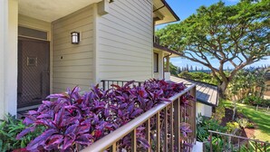 A two-story house with a covered porch, a large tree in the backyard, and a view of the ocean.