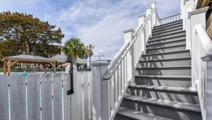 A staircase with white railings and steps, leading to a covered area with a pool.