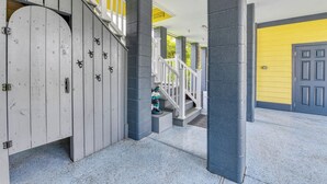A covered outdoor area with a wooden gate, a staircase, and a yellow wall.