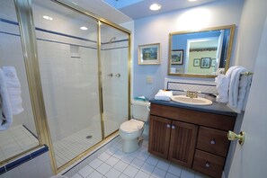 A bathroom with a glass-enclosed shower, a sink with a gold faucet, and a mirror with a gold frame. - Two Bedroom Condo with Fantastic View of Fall River from the Spacious Deck. (Estes Park)