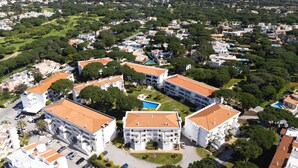 Vue aérienne d’un quartier résidentiel comprenant plusieurs immeubles, des espaces verts et une piscine.